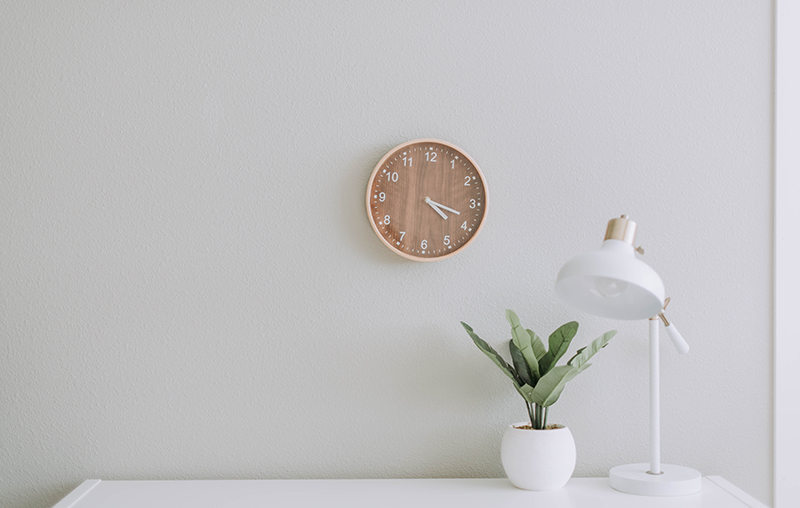 simple white desk on a white wall with a plant on the far right side